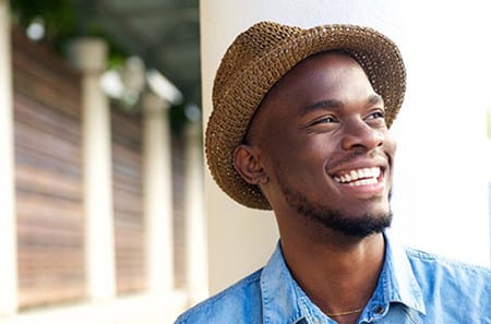 Head-and-shoulders outdoor photo of African American man wearing a hat and smiling, for sedation dentistry from Kentucky Dental Group of Lexington.