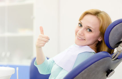 Woman giving thumbs up in a dental chair